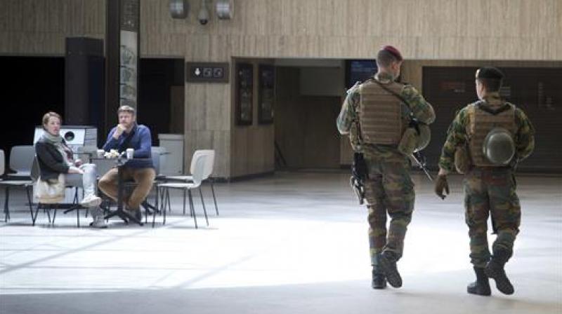 Two Belgian soldiers walk by a couple in a cafe as they patrol at Brussels Central train station in Brussels