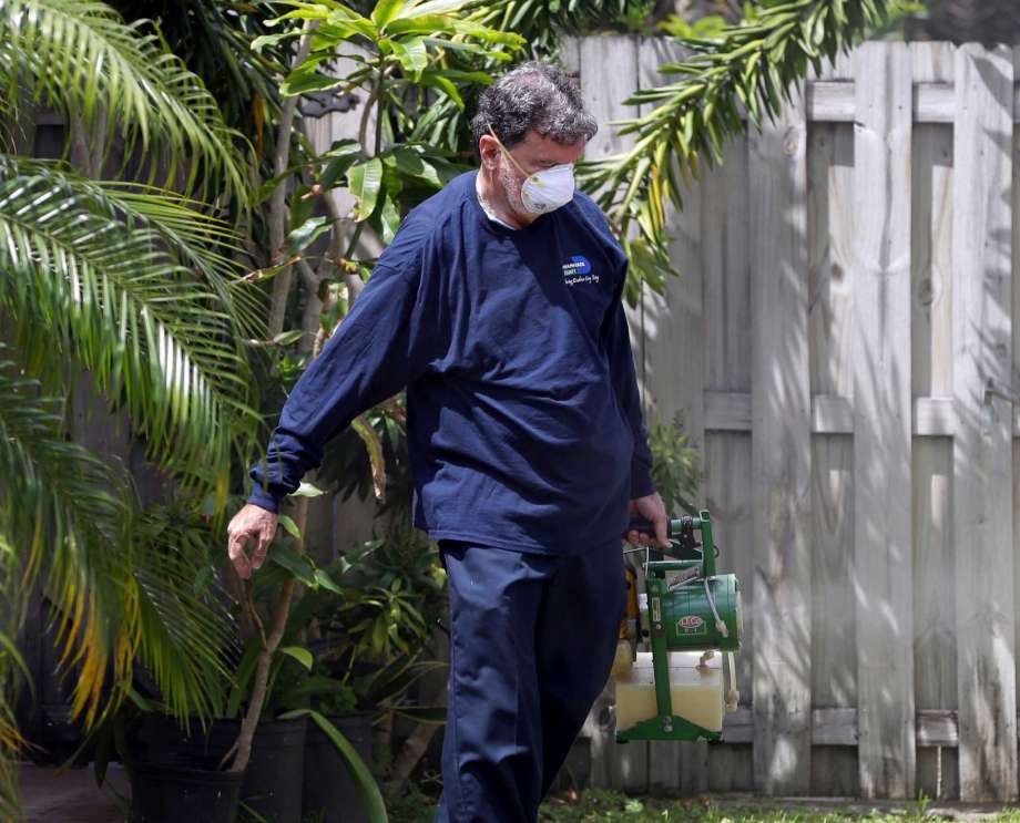 Giraldo Carratala an inspector with the Miami Dade County Fla. mosquito control unit sprays pesticide in the yard of a home in Miami Fla. On Tuesday