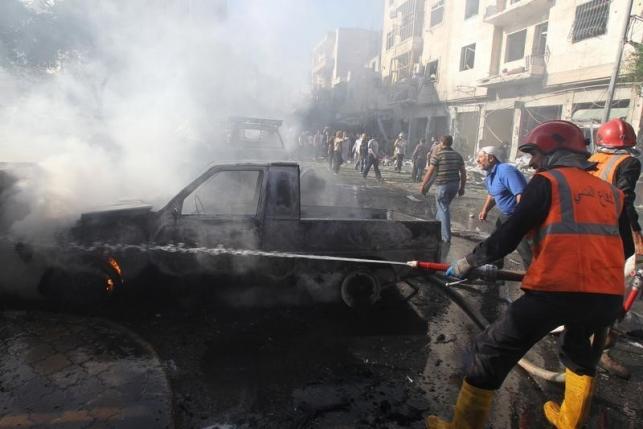 Civil defence members try to put out a fire at a site hit by airstrikes in Idlib city Syria