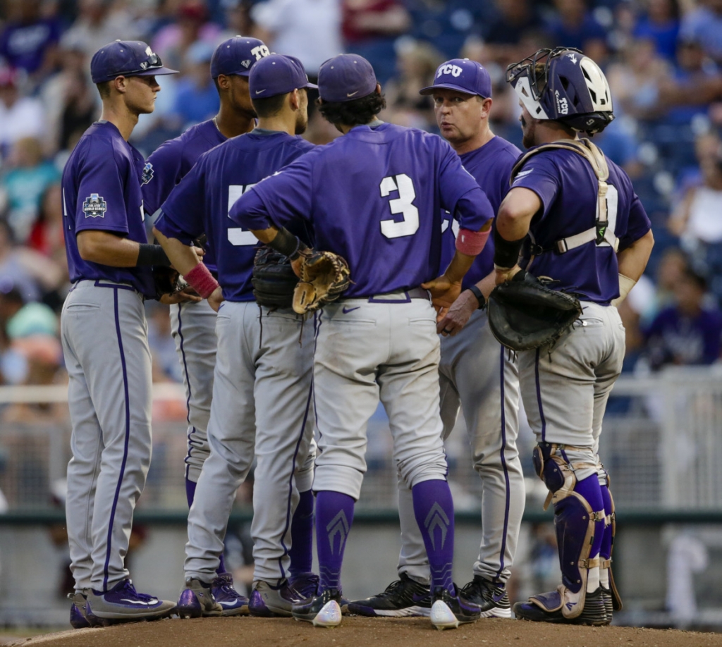 TCU coach Jim Schlossnagle second from right talks to his players during a trip to the mound during the fourth inning of an NCAA men's College World Series baseball game against Coastal Carolina in Omaha Neb. Saturday