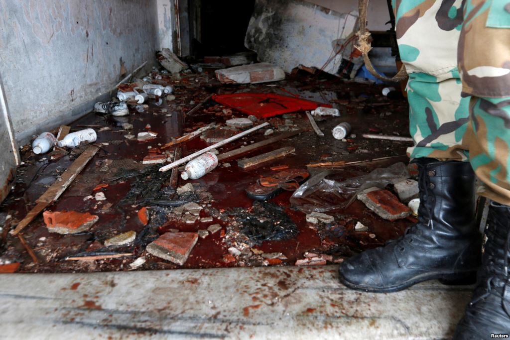 A Syrian Army soldier stands near blood on the ground of a damaged emergency room inside National Hospital after explosions hit the Syrian city of Jableh