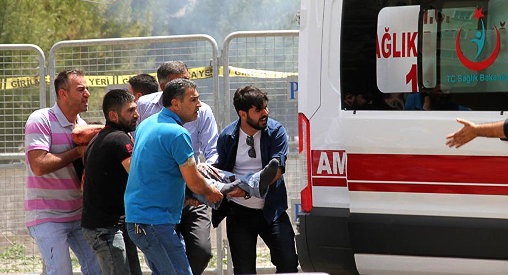 People carry an injured man towards an ambulance near the explosion site at Midyat Police station after an explosion