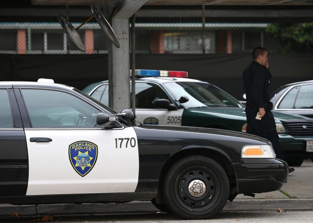 157777285-an-oakland-police-officer-walks-by-patrol-cars-at-the