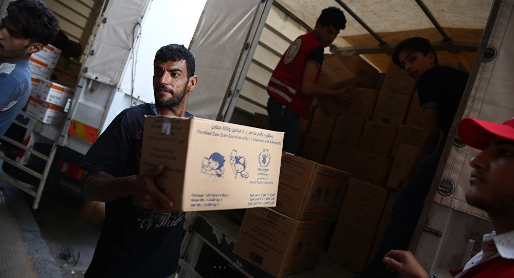 Syrians and members of the Syrian Arab Red Crescent unload a lorry after a UN and SARC aid convoy with food nutrition health and other emergency items entered the rebel-held town of Douma east of the Syrian capital Damascus