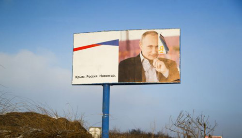 A partially damaged billboard with a portrait of Russian President Vladimir Putin is seen on a roadside near Simferopol Crimea on Jan. 24 2016. The billboard reads