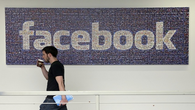 Facebook employee walks past a sign at Facebook headquarters in Menlo Park Calif. Facebook's is looking to celebs and media company videos to help engage its users