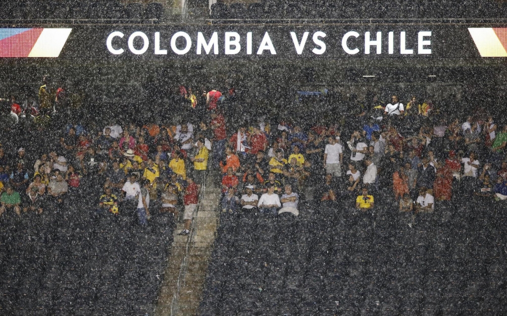 Fans sit in a heavy rain during a Copa America semifinal soccer match between Chile and Colombia at Soldier Field in Chicago