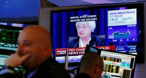 Traders work as Federal Reserve Chair Janet Yellen speaks on a television above the floor of the New York Stock Exchange shortly after the opening bell in New York City