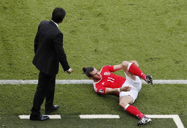 Wales&#39 Gareth Bale falls alongside Wales coach Chris Coleman during the Euro 2016 round of 16 soccer match between Wales and Northern Ireland at the Parc des Princes stadium in Paris Saturday