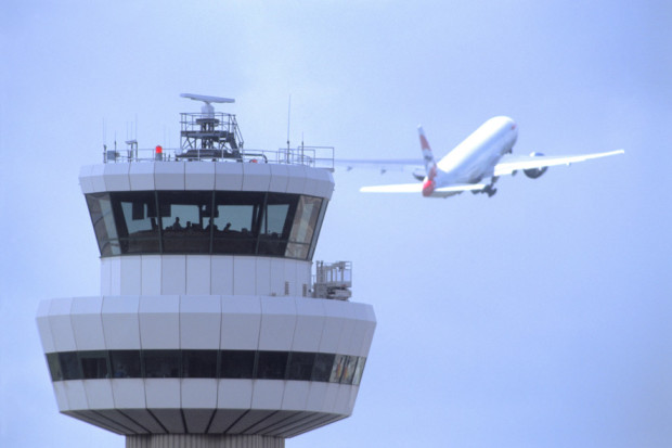 Gatwick Airport control tower with aircraft in flight in background SUS-150705-150051001