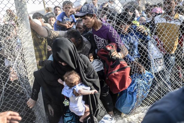 Syrian refugees climb through a broken border fence on the Turkish border in 2015