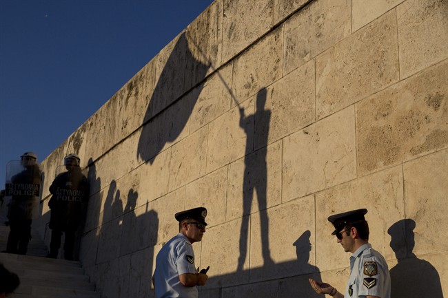 The shadow of a demonstrator waving a flag is cast on a wall as Greek police officers secure the Greek Parliament during a protest in central Athens Wednesday