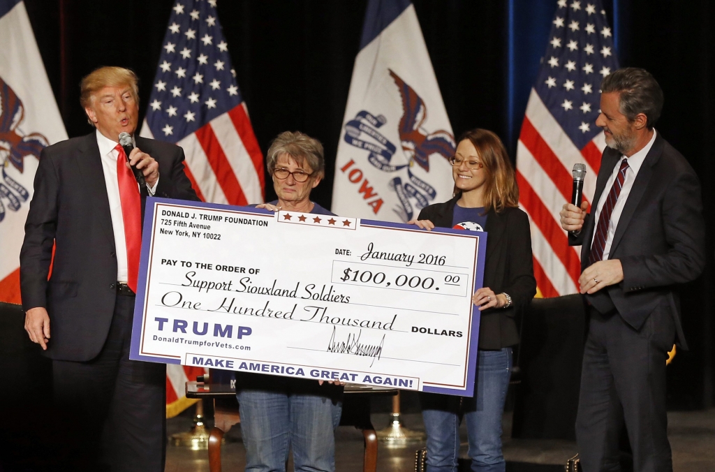 Republican presidential candidate Donald Trump left presents a check to members of Support Siouxland Soldiers during a campaign event at the Orpheum Theatre in Sioux City Iowa. Under pressure to account for mone