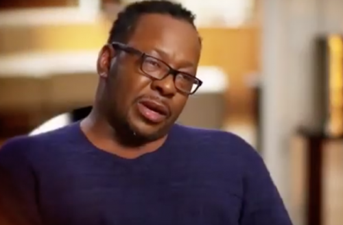 Bobby Brown in blue sweater black glasses