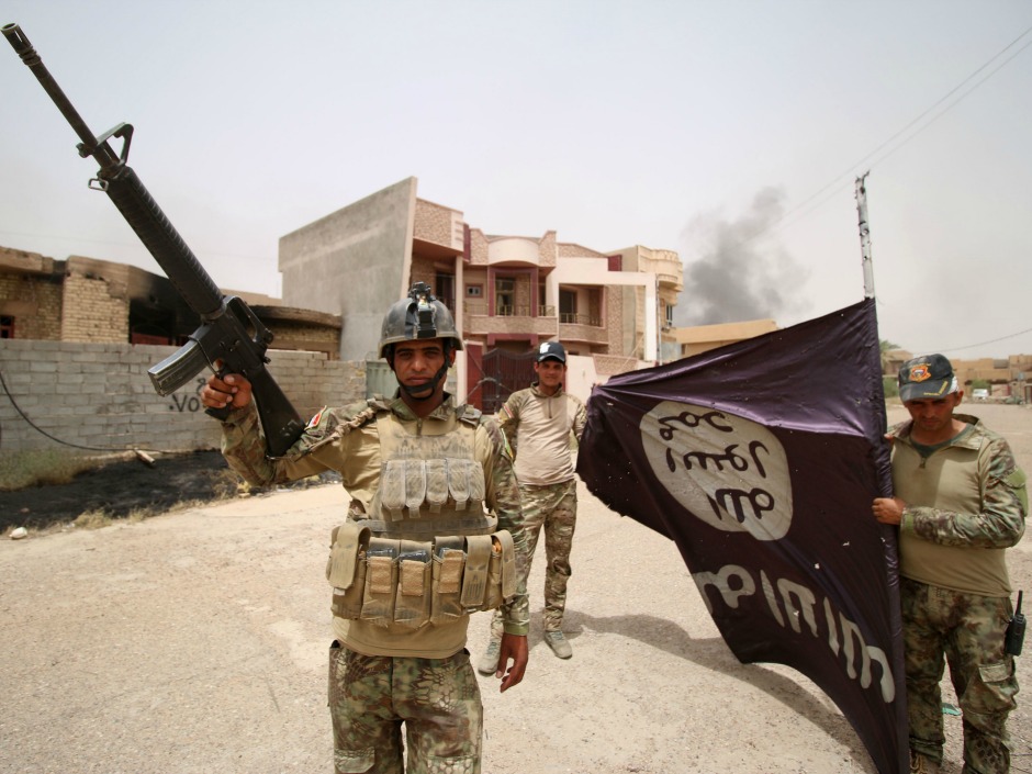 Iraqi pro-government forces hold an Islamic State flag in Fallujah as they try to clear the city of ISIL fighters on June 19