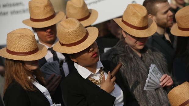 German activists wearing suits and Panama hats hold fake money while demanding greater transparency following the Panama