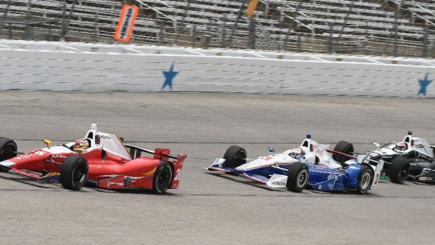 Carlos Munoz, of Colombia leads Helio Castroneves, of Brazil and Alexander Rossi on the first lap of an Indy Car auto race at Texas Motor Speedway Sunday