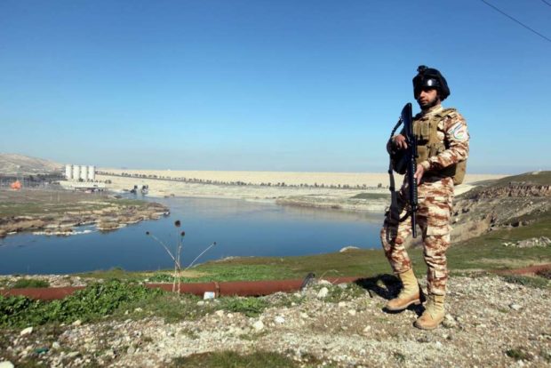 An Iraqi Kurdish Peshmerga stands guard near the Mosul Dam in northern Iraq