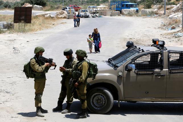 Israeli soldiers stand guard at the entrance of Yatta near the West Bank city of Hebr