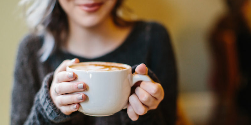 Close up of girl holding big white mug of coffee