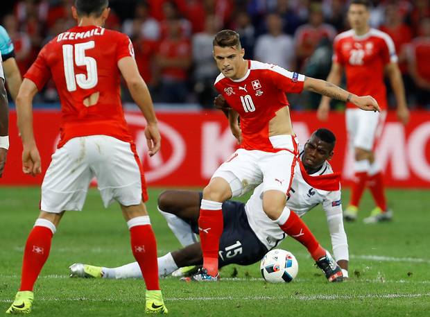 Letting rip Swiss midfielder Granit Xhaka plays on with a torn shirt