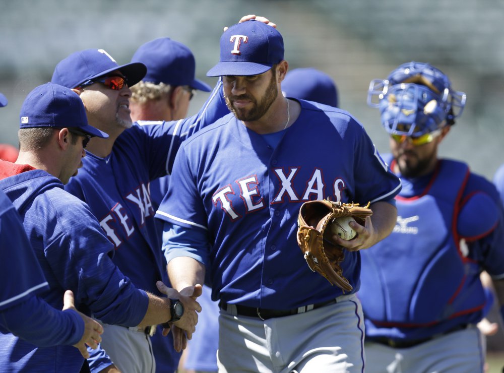 Texas pitcher Colby Lewis is congratulated after his two-hit win Thursday against the Athletics at Oakland California. Lewis who had a perfect game for 7 innings improved to 6-0 on the year