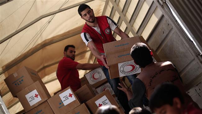 Members of the Syrian Arab Red Crescent deliver aid boxes to the militant-held town of Douma near the Syrian capital