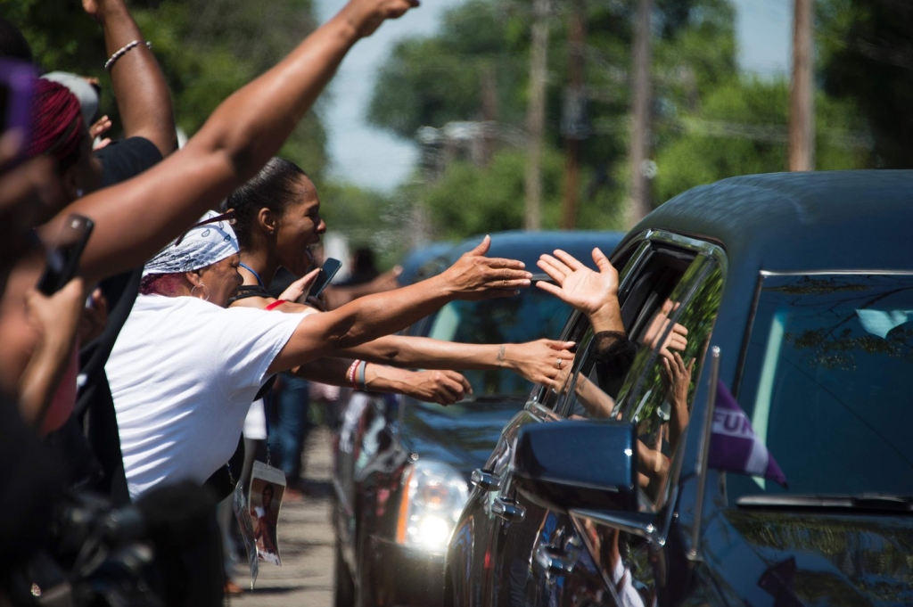 People reach out to the limousines in boxing legend Muhammad Ali's procession as it drives past his childhood home where mourners waited to pay their respects