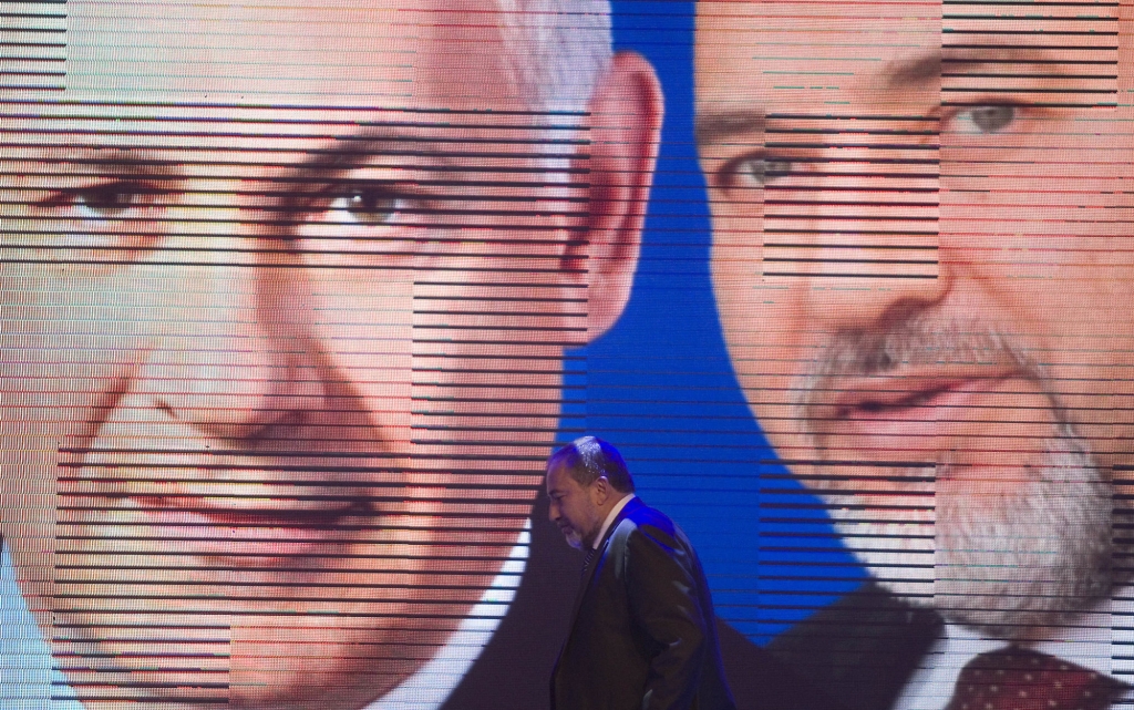 Israeli Foreign Minister Avigdor Lieberman walks under a screen showing him and Israeli Prime Minister Benjamin Netanyahu during the inauguration of their election campaign in Jerusalem. Israel ™s inco