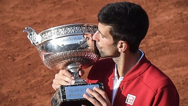 Novak Djokovic poses with the championship trophy after winning the French Open