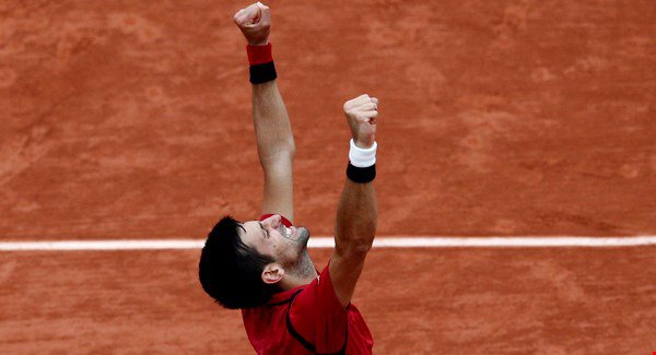 Novak Djokovic raises his arms in victory after defeating Austria’s Dominic Thiem during their semifinal match of the French Open