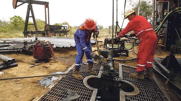 Men work at an oil pump in Lagunillas Ciudad Ojeda in Venezuela