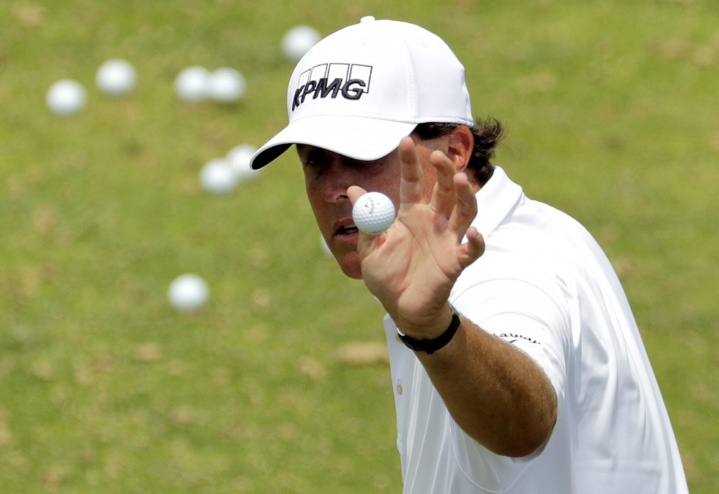 Phil Mickelson catches a ball from his caddie on the driving range before a practice round for the U.S. Open golf championship at Oakmont Country Club on Wednesday