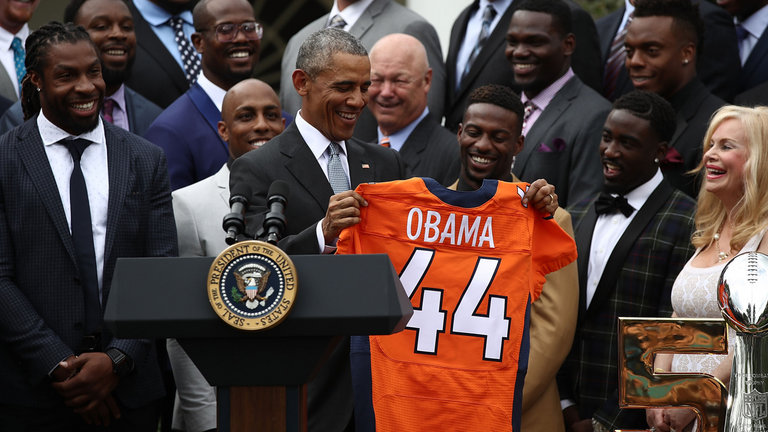 Obama holds up a Denver Broncos jersey presented to him as a gift