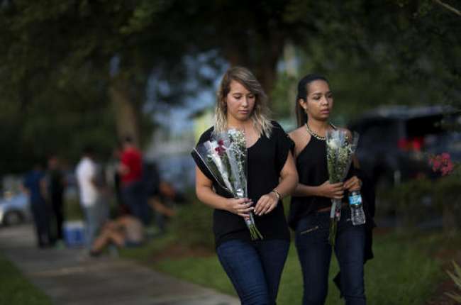 Mourners carry flowers into the visitation for Pulse nightclub shooting victim Javier Jorge Reyes Wednesday