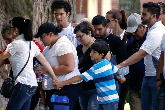 A boy creates a cordon around family members as they leave a senior citizen's center after being notified about the fate of their loved ones one day after a mass shooting at the Pulse gay night club in Orlando Florida U.S