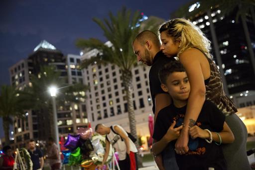 Jennifer Johnson right leans on her boyfriend Jeansem Sambolin while standing with her son Tyrone Clarke 8 as they visit a makeshift memorial for the victims of the mass shooting at the Pulse Orlando nightclub Tuesday