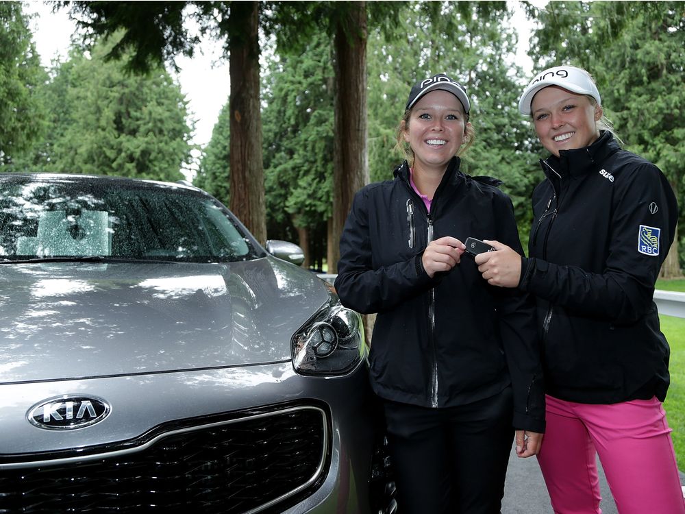 Brooke Henderson of Smiths Falls Ont. and her sister  caddie Brittany pose next to a Kia after Brooke made a hole in one on the 13th hole during the first round of the KPMG Women's PGA Championship at the Sahalee Country Club