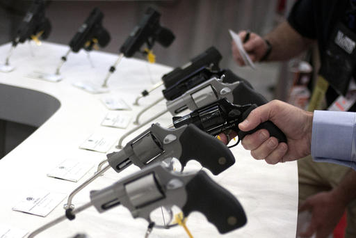 Man holds a gun in the exhibit hall of the George R. Brown Convention Center the site for the NRA's annual meeting in Houston Texas