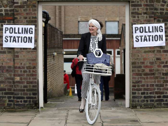 A woman on a bicycle leaves a polling station near to the Royal Chelsea Hospital London Thursday. Associated Press