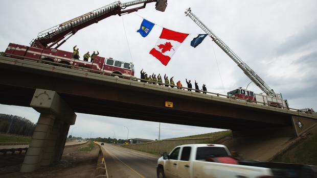 Police and firefighters wave to returning evacuees after a massive wildfire in Fort McMurray Alberta Canada