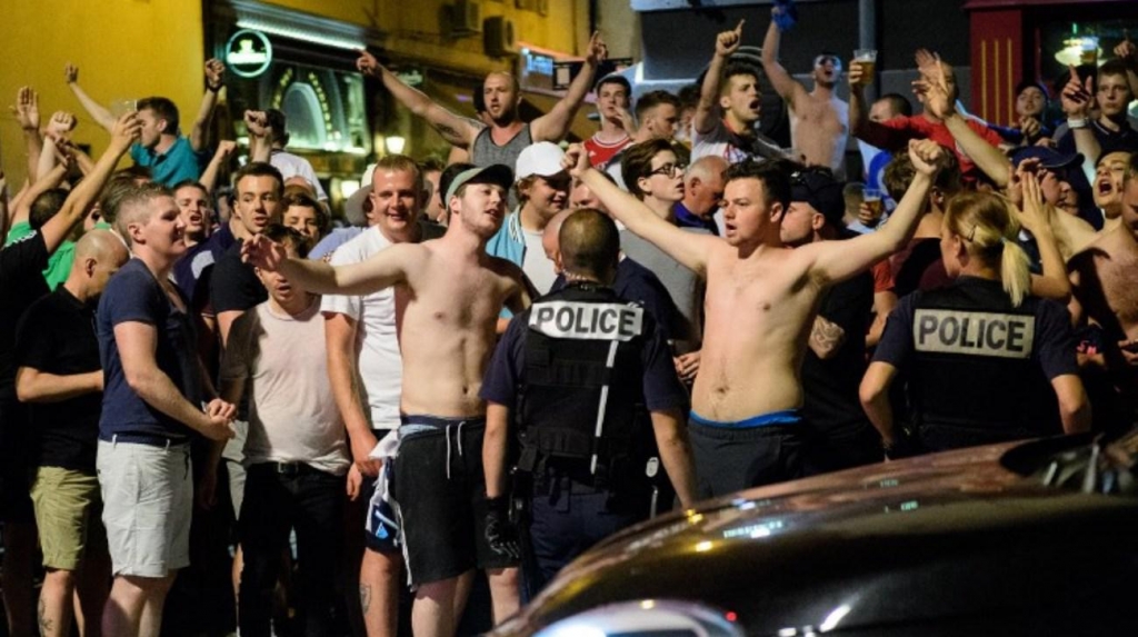 Police stand guard as England fans gather and chant slogans in the port area of Marseille late