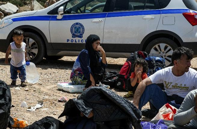 Refugees and migrants wait by a police car in Crete after being rescued from another capsized vessel on May 31