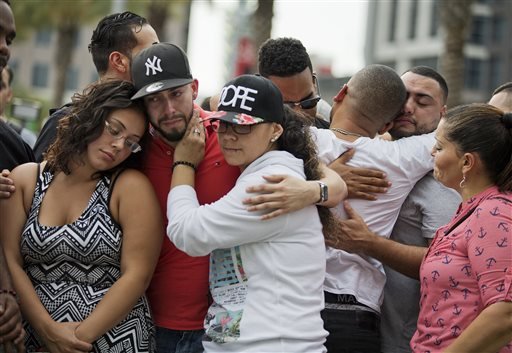 Mourners console each other as they grieve the loss of their friends Amanda Alvear and Mercedez Flores who were killed in the mass shooting at the Pulse nightclub as they visit a makeshift memorial downtown Monday