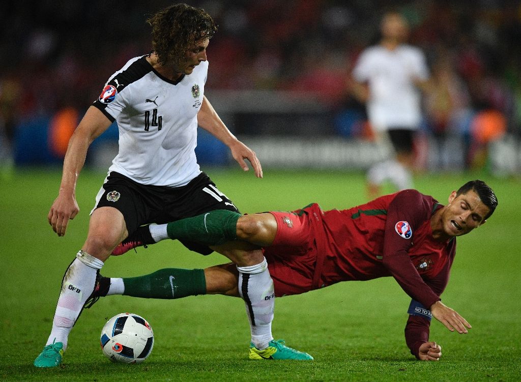 Portugal's forward Cristiano Ronaldo falls on the pitch as he vies with Austria's midfielder Julian Baumgartlinger during the Euro 2016 group F football match between Portugal and Austria at the Parc des Princes in Paris