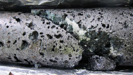 Section of rock core from the CO2 storage reservoir showing vesicular basalt with a well-defined fracture with calcium carbonate mineralization