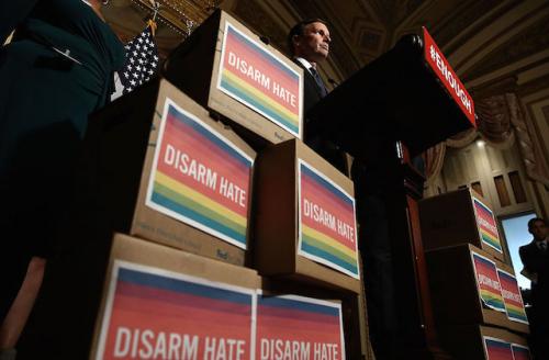 Man stands at podium flanked by boxes with signs that read'Disarm Hate