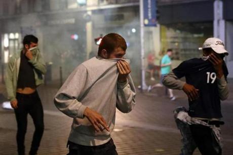 LILLE FRANCE- JUNE 15 People cover their faces as they run after tear gas is fired as French riot police encounter hundreds of drunken English football fans