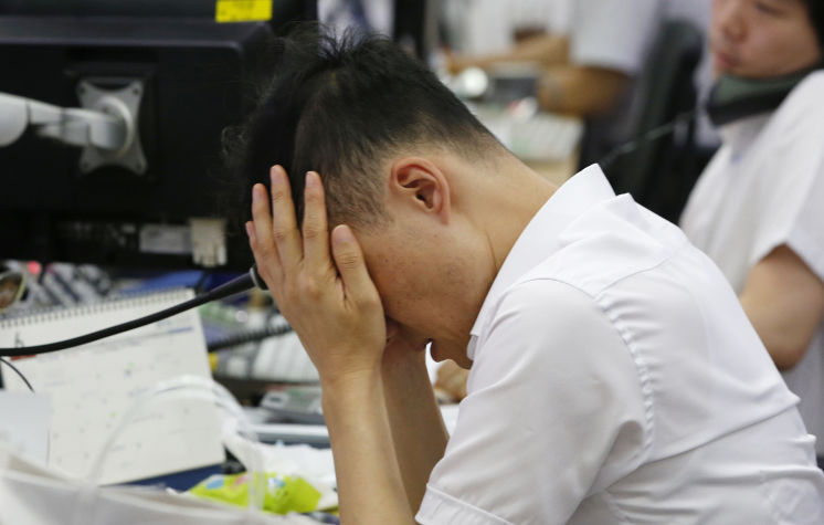 A currency trader rubs his eyes at the foreign exchange dealing room in Seoul South Korea on Friday. Asian stock markets were volatile on Friday with Tokyo stocks and U.S. futures plunging