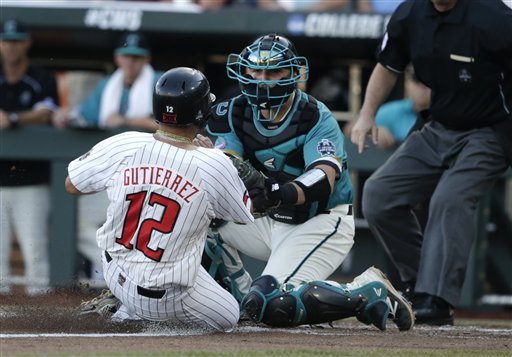 Coastal Carolina catcher David Parrett tags Texas Tech's Eric Gutierrez out at home in the second inning of an NCAA College World Series baseball game in Omaha Neb. Thursday